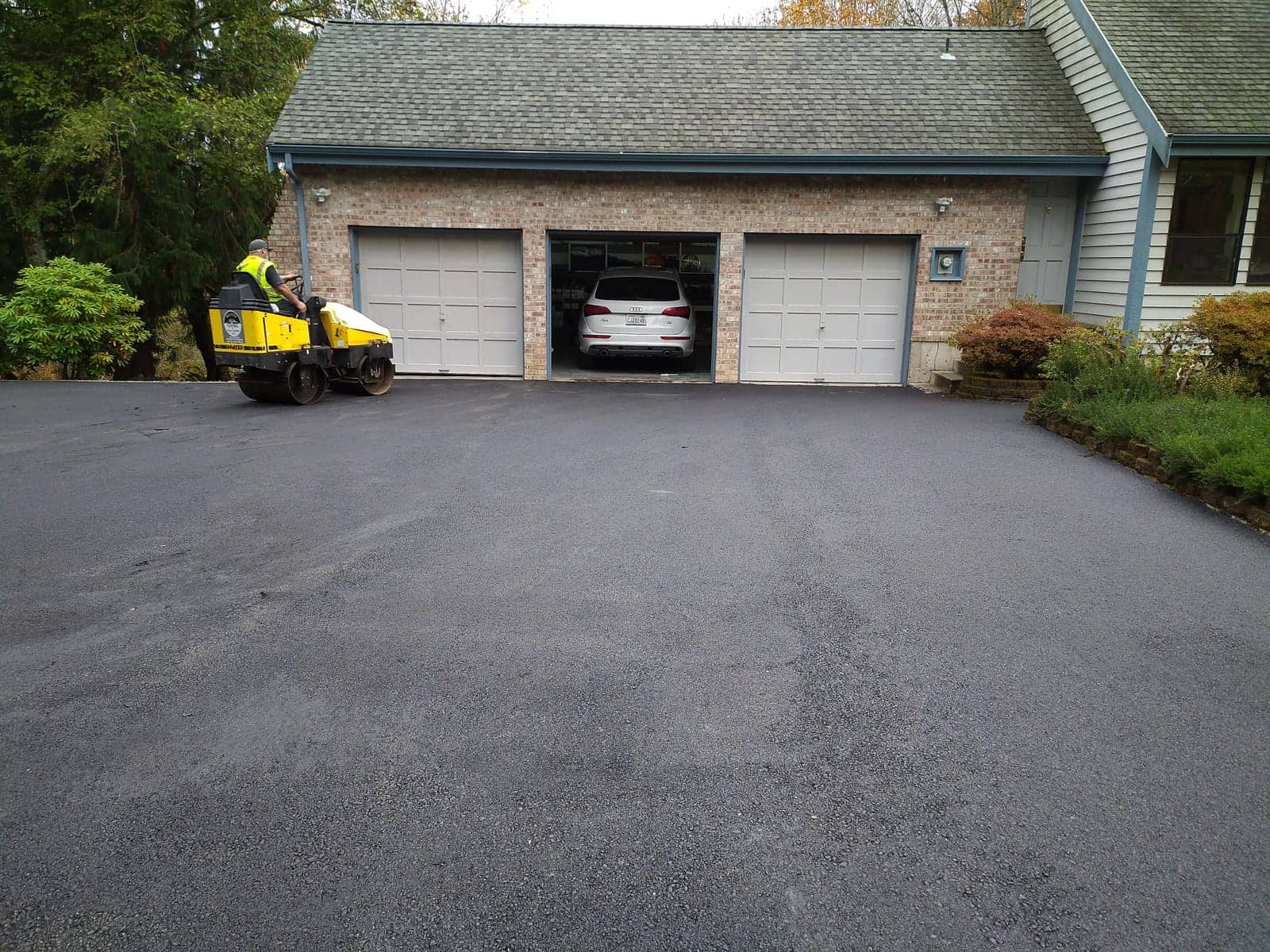 Roller compacting a residential driveway to an even, deep black finish