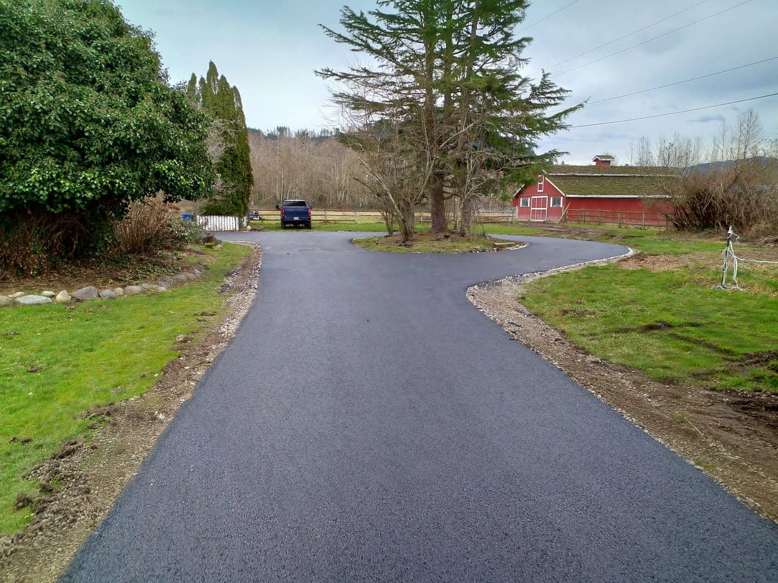 Freshly paved driveway forking across a rural property
