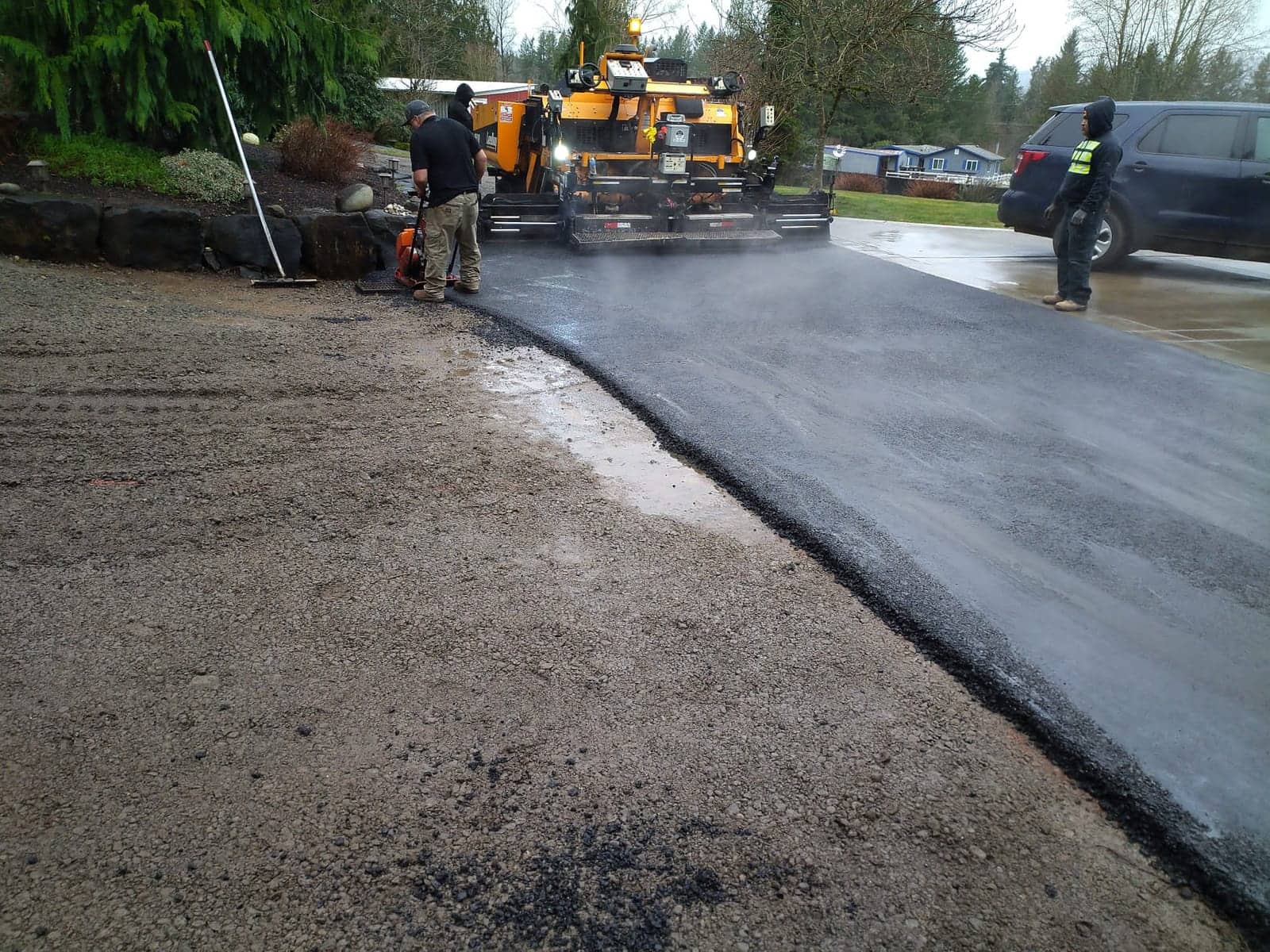 Fresh asphalt meeting the graded base of an estate driveway mid-project