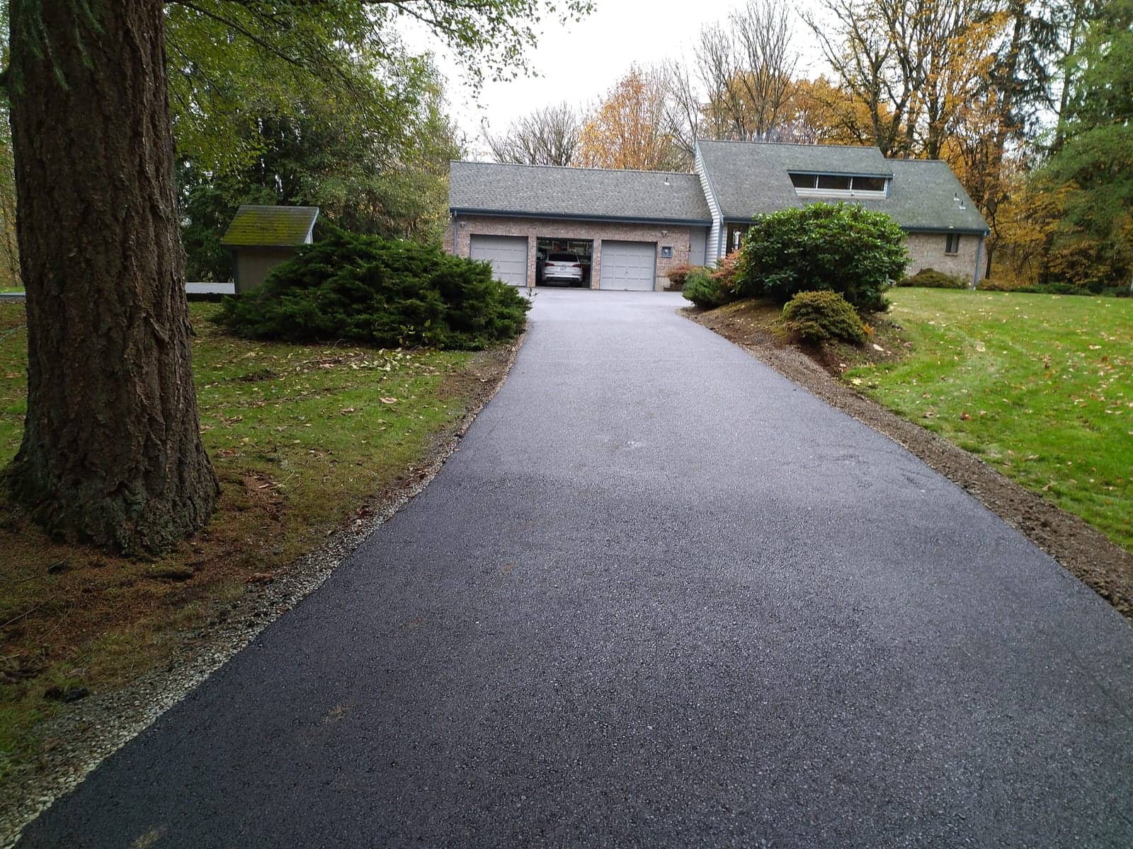 Newly paved driveway curving between lawns and mature trees
