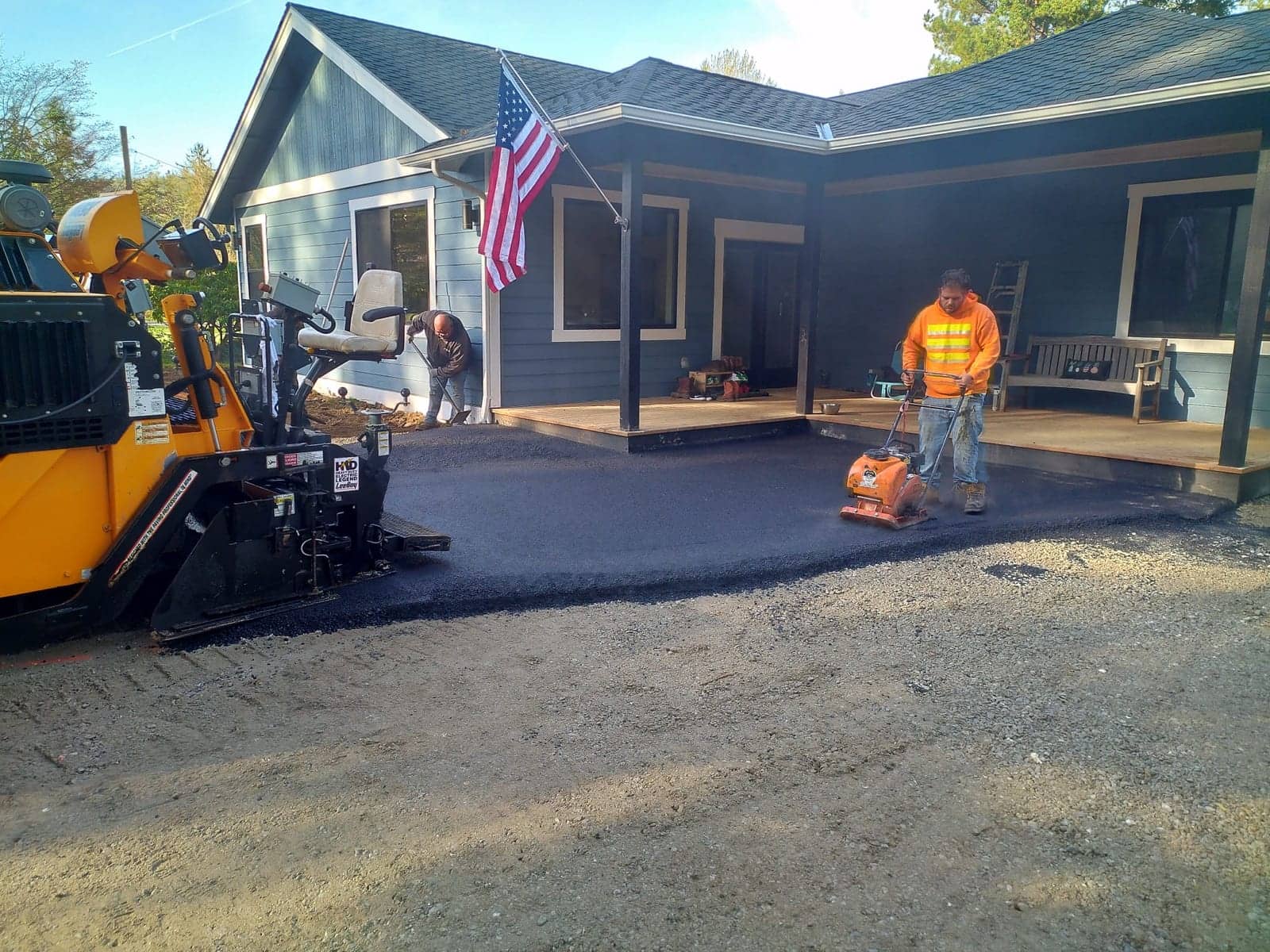 Crew and paver laying fresh asphalt at a farmhouse driveway