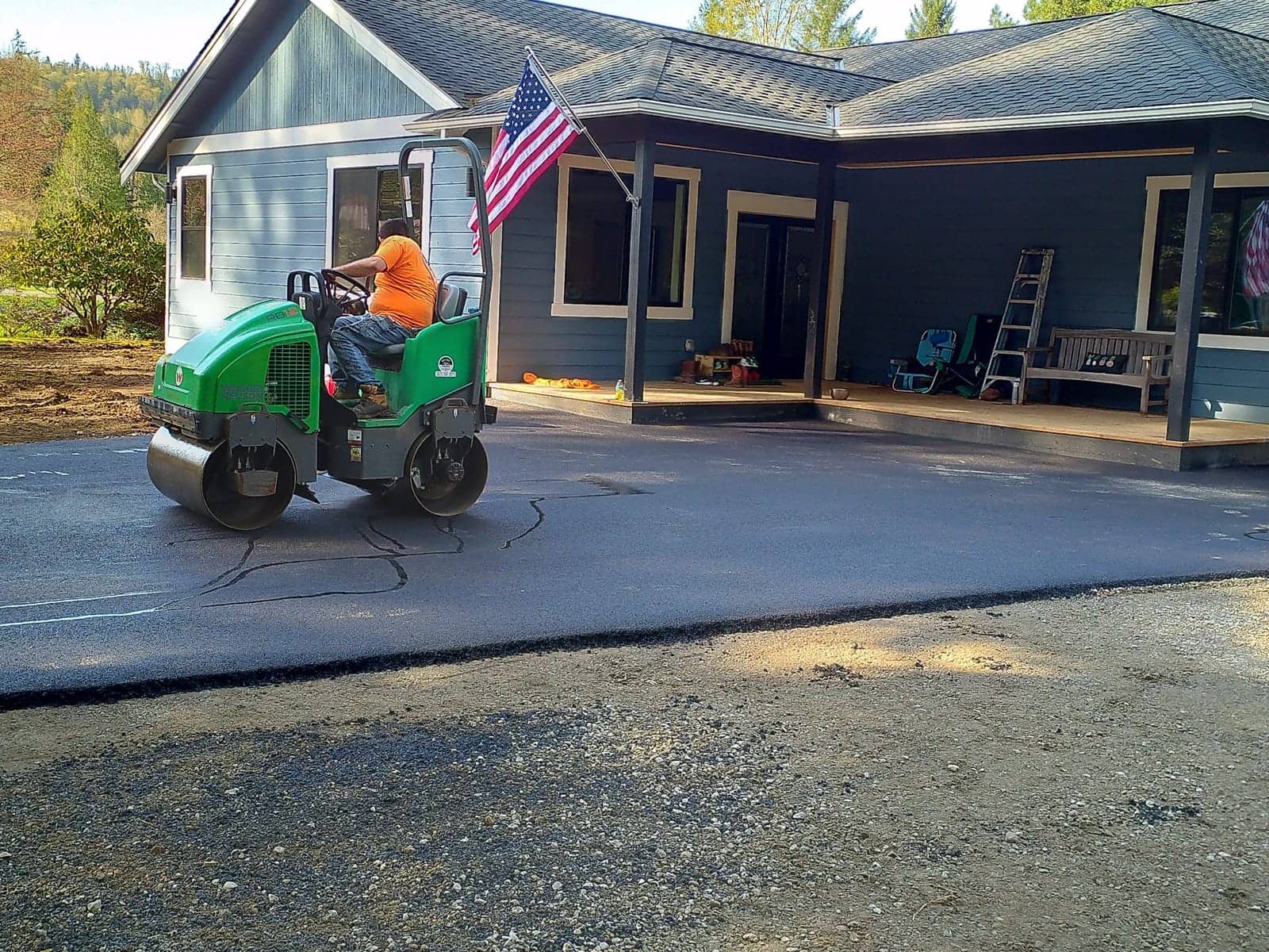 Rolling fresh asphalt in front of a farmhouse porch