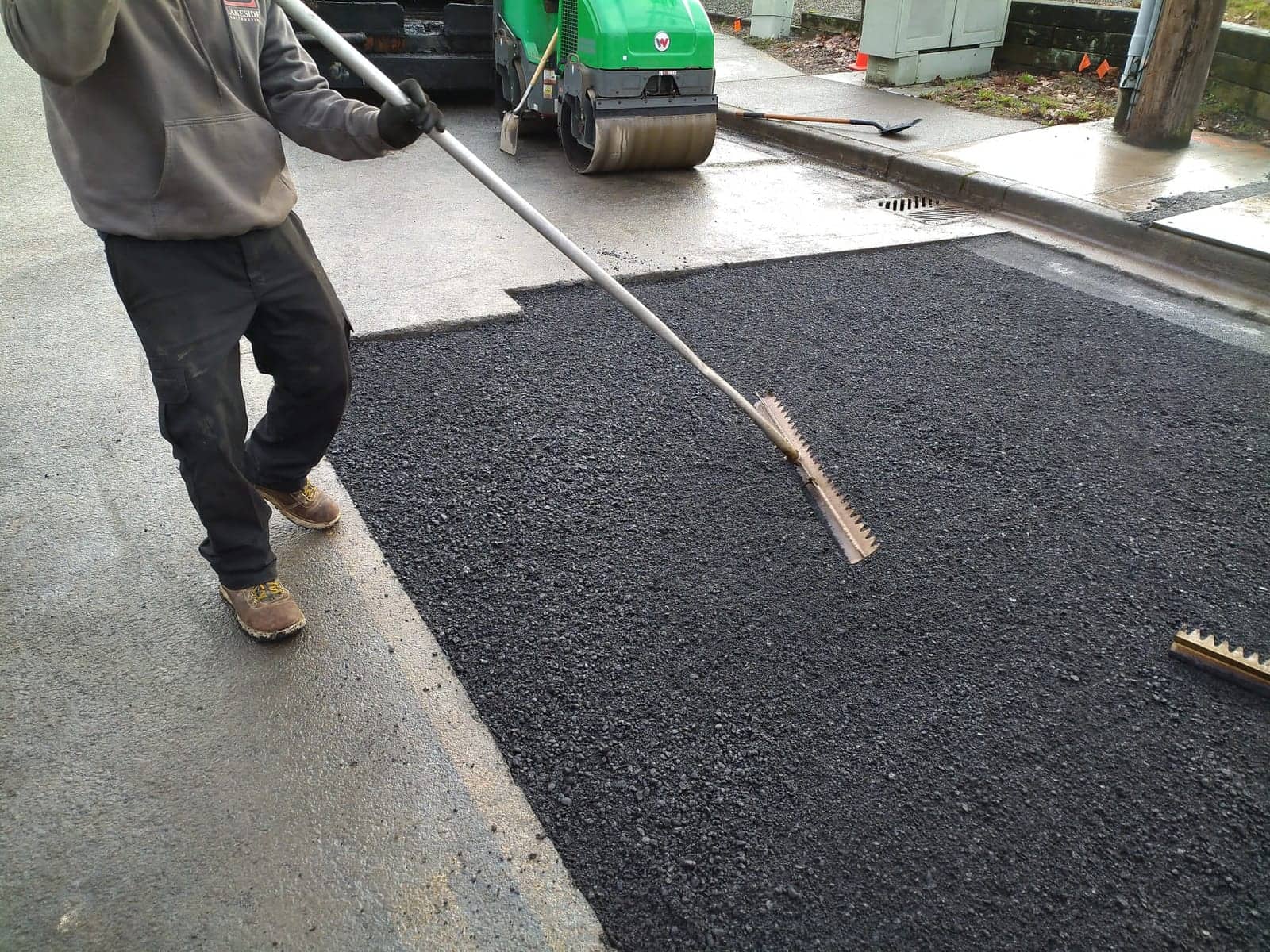 Hand-raking hot asphalt mix on a street patch