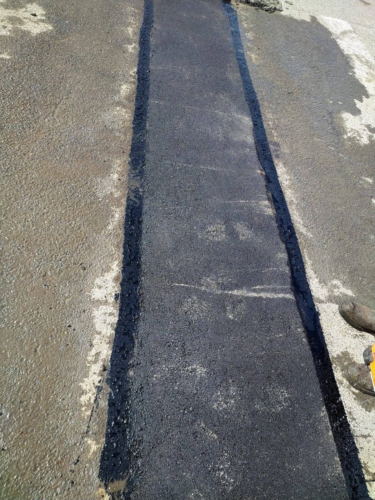 Fresh asphalt strip sealed into older pavement
