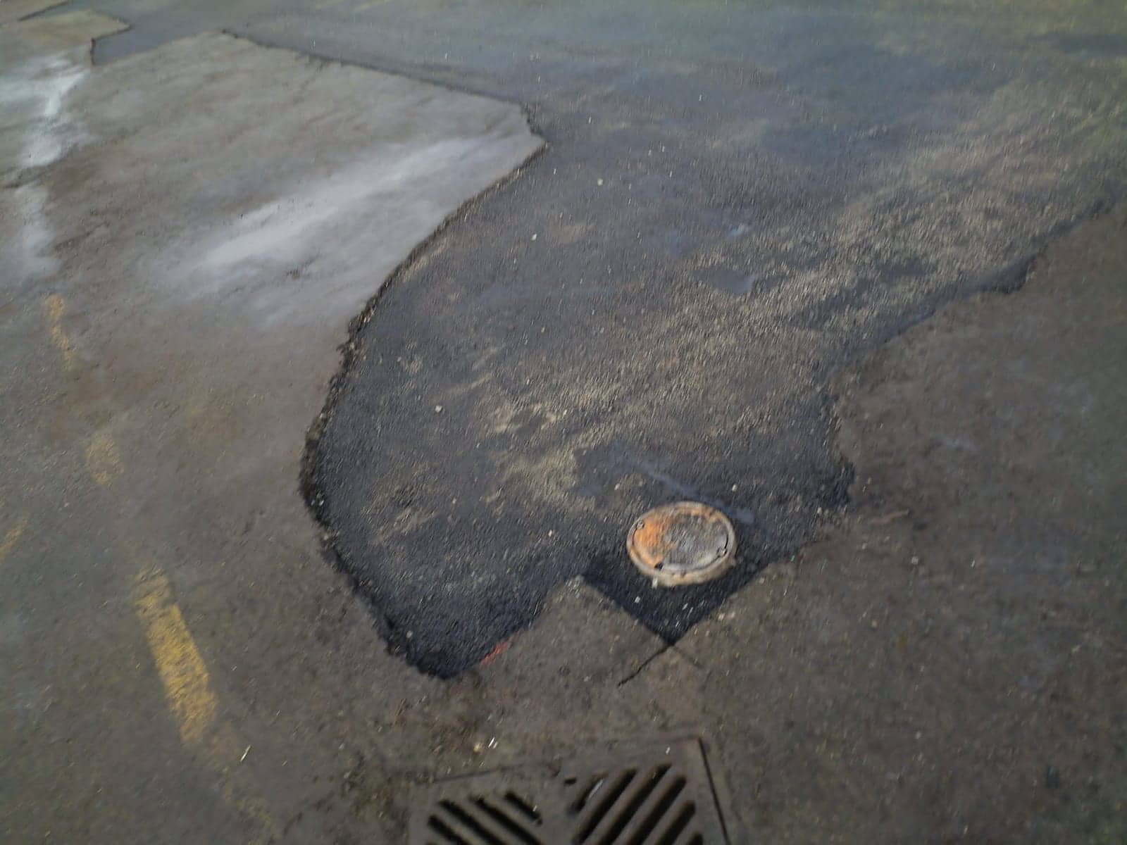 Freshly patched pothole around a utility cover