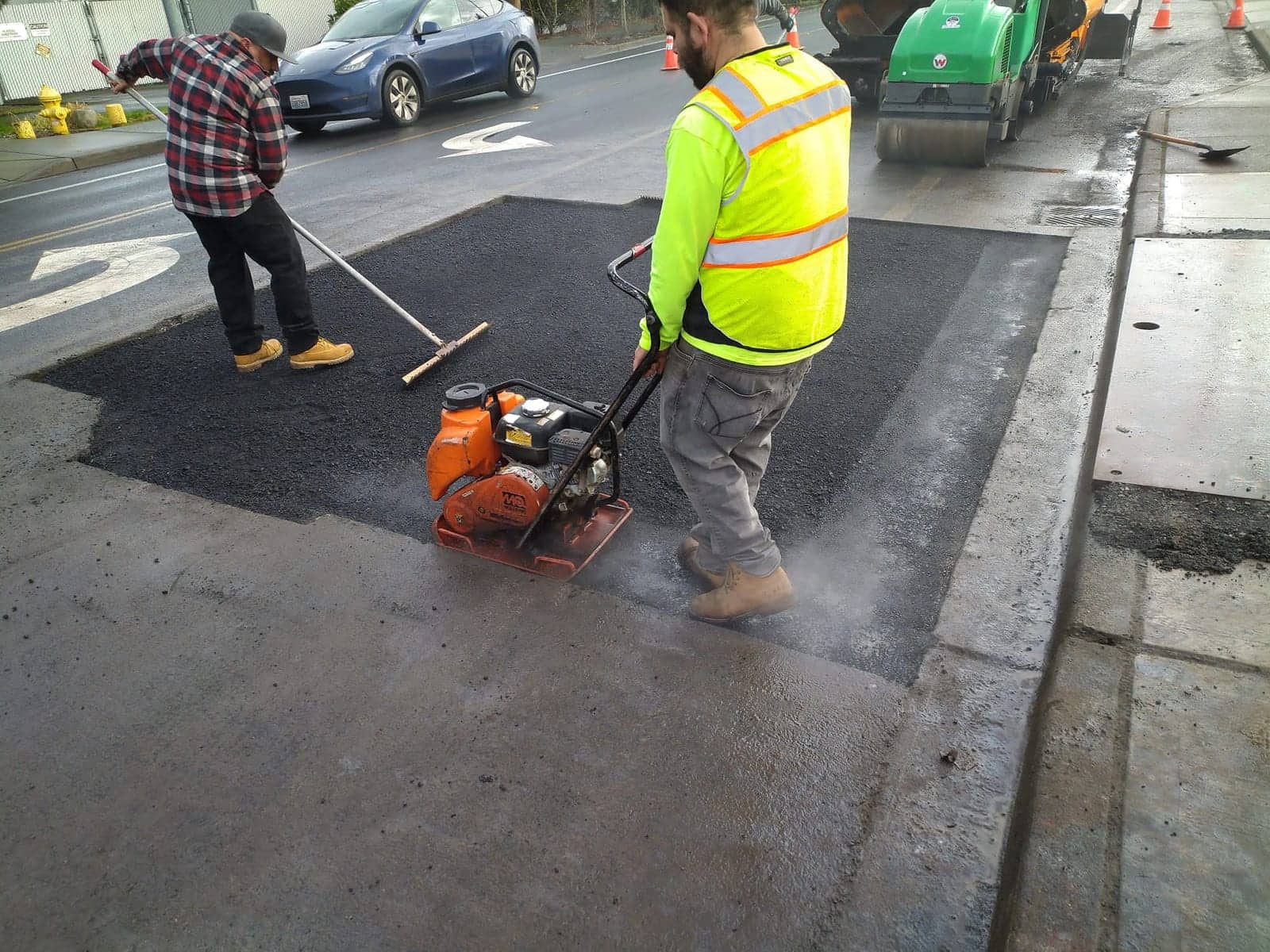 Crew compacting a fresh asphalt street repair