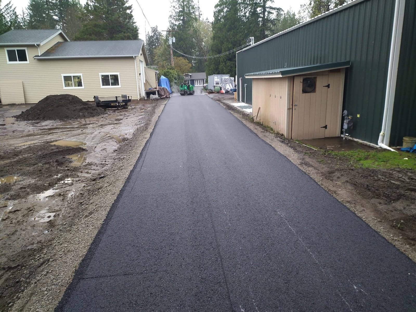 Long freshly paved lane beside a workshop building
