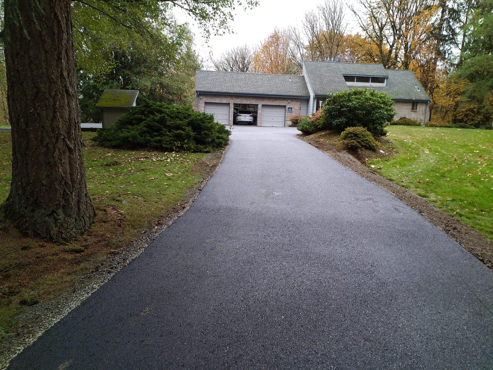 Newly paved driveway curving between lawns and mature trees
